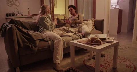 Diverse girlfriends drinking wine on sofa with new clothes Stock Footage 259720194