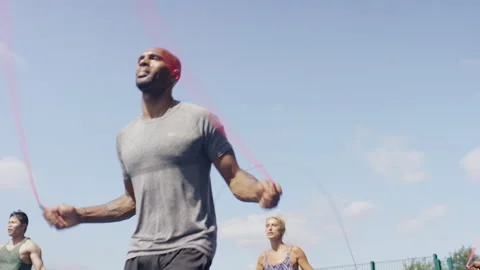 Diverse group of active people skipping with jump ropes in unison in a park, in  Stock Footage