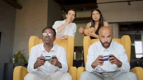 Diverse group of colleagues plays an exciting game console in their office break 스톡 동영상 335764768