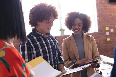 Diverse group of creative colleagues in discussion at work using tablets taking Stock Photos