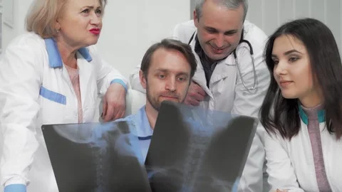 Diverse group of doctors analyzing x-ray scans with focused expressions Stock Footage 311982805