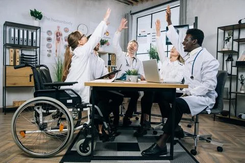 Diverse group of doctors smiling gesturing with arms raised after meeting Фото