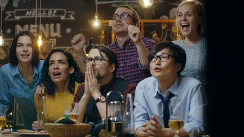 Diverse Group of Friends Watches TV in the Sporstbar. Their Team Scores the Goal Stock Footage