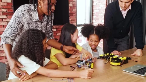 Diverse group of kids learning robotics and coding with teacher guidance. Video stock 312192896