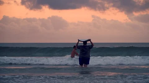 A diverse group of people can be seen surfing in the ocean at sunset Stock Footage 312326253