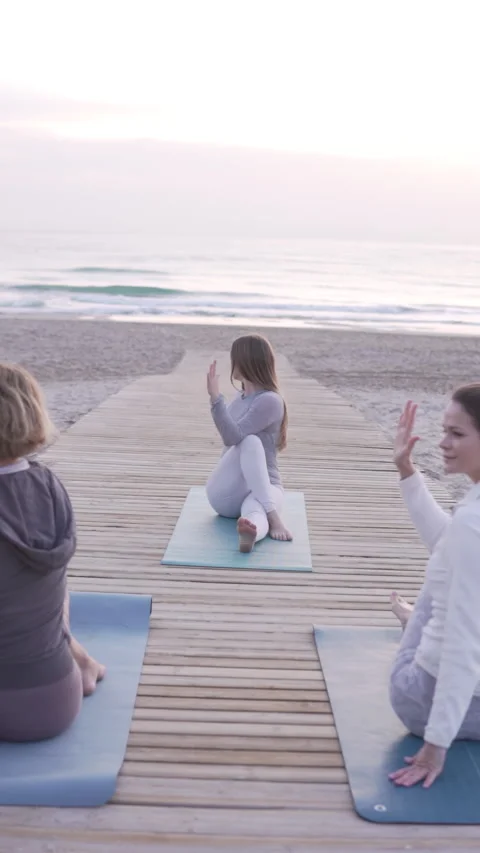 A diverse group practices calming yoga on a serene ocean pier Stock Footage 303406651