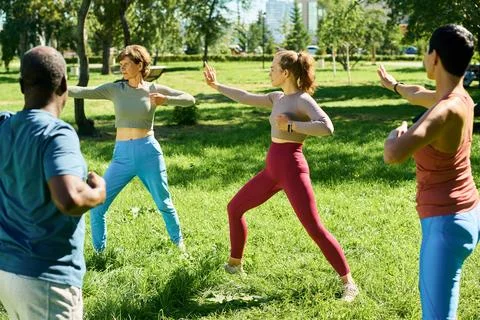 Diverse Group Practicing Tai Chi Exercises in Sunny Park Foto stock