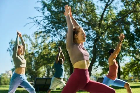 Diverse Group Practicing Yoga Together in Outdoor Park Class Foto stock