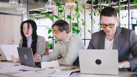 A diverse group of professionals collaborates in a modern office with laptops Stock Footage 292461346