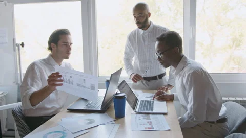 Diverse group of professionals collaborates in an office setting. They work on Vídeos de archivo 335731704