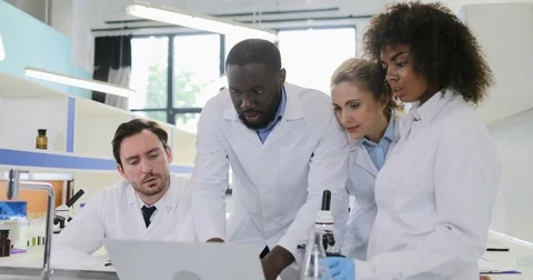 Diverse Group Of Scientists In Laboratory Looking At Laptop Computer Talking Stock Footage 77222425