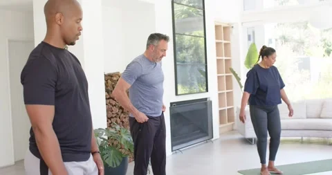 Diverse group stepping onto green mats, aligning feet while instructor in blue Stock Footage 339592105