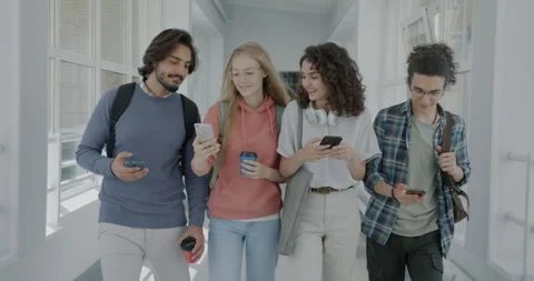 Diverse group of students walking in college hallway enjoying smartphone content Vídeos de archivo 245230762