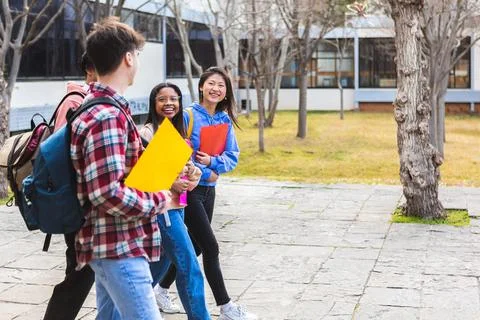 Diverse group of teenage student friends walking outside at high school Stock Photos