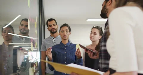 Diverse group of work colleagues brainstorming putting sticky notes on glass Stock Footage 154792212