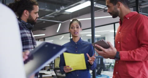 Diverse group of work colleagues standing holding documents and tablet talking Stock Footage 154791864