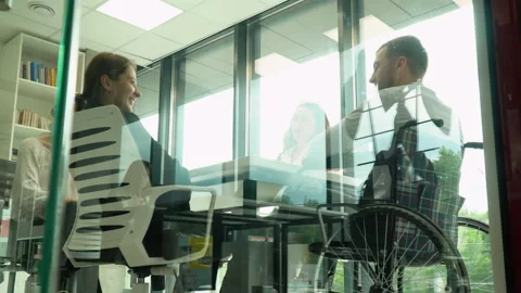 Diverse group of work colleagues talking at office meeting, one in wheelchair Video stock 196263784