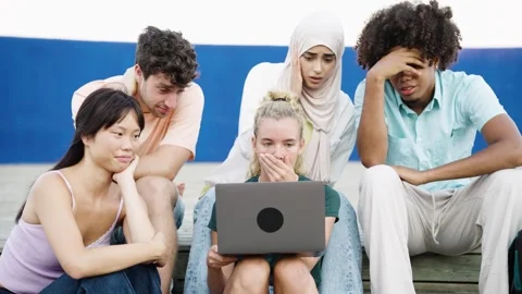 Diverse group of young friends watching shocking content on a laptop computer Stock Footage 335600560