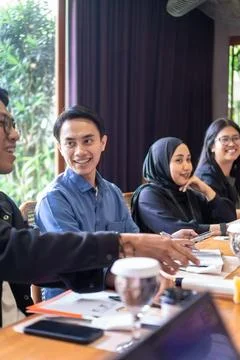 Diverse group of young professionals collaborating in a modern office meeting Stock Photos