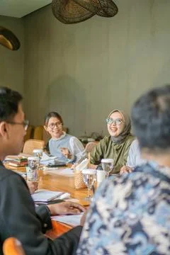 Diverse group of young professionals collaborating in a modern office meeting Stockfoto's