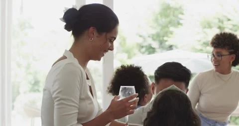 Diverse guests laughing and sharing wine after host offering rosé at home around Stock Footage 316578747