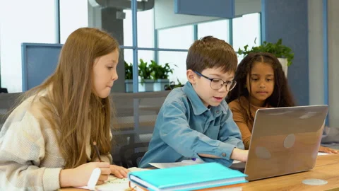 Diverse happy school kids using laptop computer together in classroom. Back to Video stock 258474103