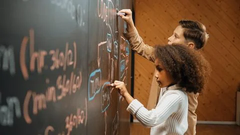 Diverse happy students brainstorm engineering prompt on blackboard. Erudition. Stock-Fotos