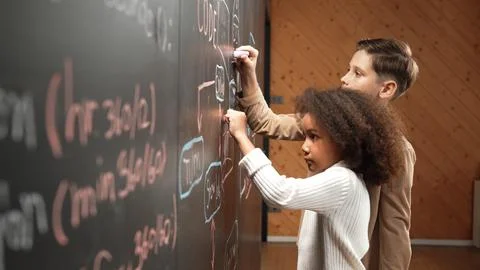 Diverse happy students brainstorm engineering prompt on blackboard. Erudition. Stock-Fotos