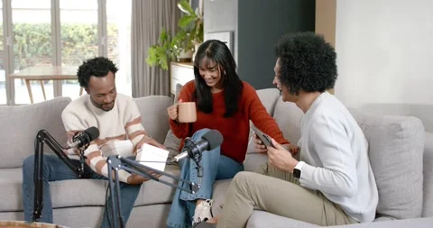Diverse hosts podcasting with mics, left host opening white box, gesturing, Stock Footage 345607758