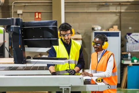 Diverse industrial workers collaborating on cnc machine control Stock Photos