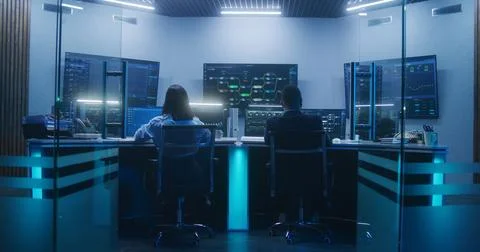 Diverse IT technical specialists work on computers in monitoring office Stock Photos