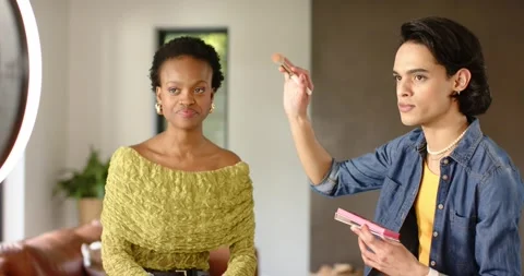Diverse makeup artist and model adjusting ring light and demonstrating blush Stock Footage 337400087