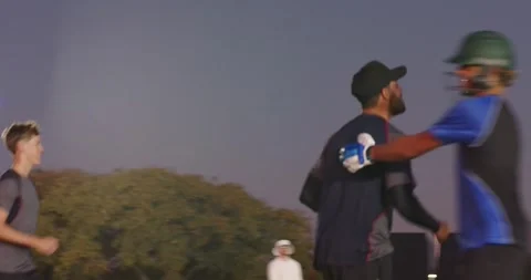 Diverse male baseball team practicing batting on field at dusk, gloves, cage Stock Footage 337293752