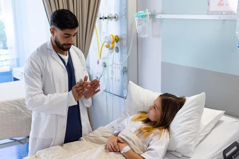 Diverse male doctor with asthma inhaler explaining to girl patient in hospi.. Stock Photos