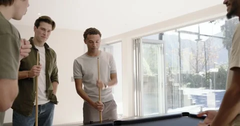 Diverse male friends placing triangular rack on black felt pool table, chatting, Stock Footage 339959641