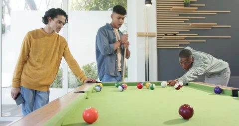 Diverse male friends at pool table, African American man aligning and striking Stock Footage 344948196