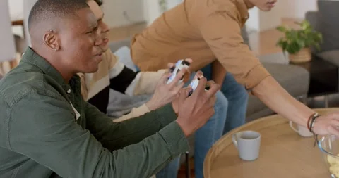 Diverse male friends pressing controller buttons snacking chips, coffee sipping Stock Footage 343239795