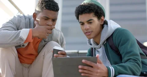 Diverse male friends pulling tablet from bag, swiping, studying on school steps Stock Footage 337932830