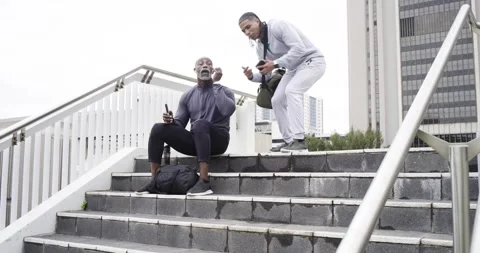 Diverse male strangers exchanging smartwatch tips on urban stairs after shoulder Stock Footage 340972353