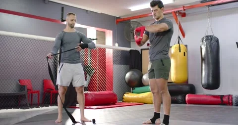 Diverse male training partners pulling inspecting red and black wraps on mat Stock Footage 339413300