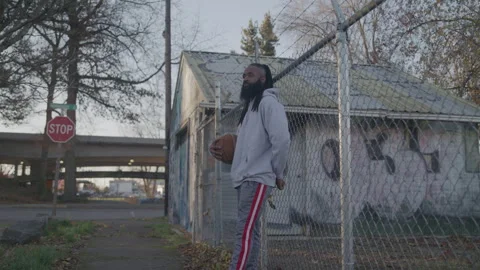 Diverse Man with Dreadlocks and Beard Holds Basketball Downtown at Sunset Stock Footage 270397650