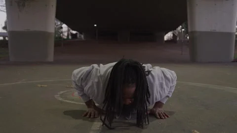Diverse Man with Dreadlocks and Beard Does Burpees Under Bridge at Sundown Stock Footage 270400365