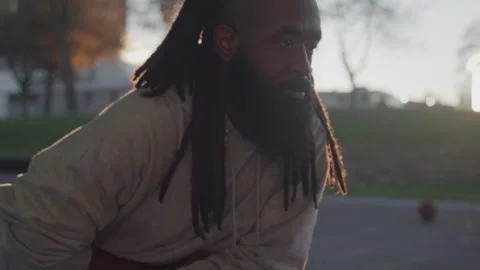 Diverse Man with Dreads and Beard Streches on Outdoor Basketball Court at Sunset Stock Footage 270399031