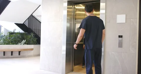 Diverse med staff calling elevator at lobby, woman emerging, man showing tablet, Stock Footage 342233362