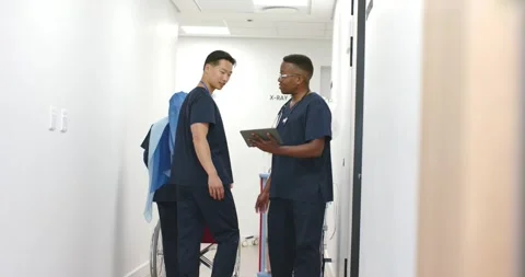 Diverse med team in scrubs using tablet confirming exam pointing to X-RAY Stock Footage 340257193