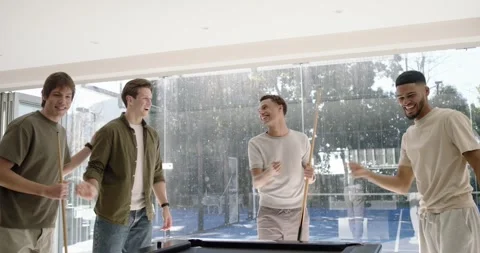 Diverse men breaking rack, player striking cue ball at black-felt pool table at Stock Footage 339959649