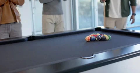 Diverse men in game-room at pool table player placing cue aligning ball breaking Stock Footage 342068598