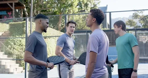 Diverse men gathering at net on paddle court, juggling ball, tapping paddles, Stock-Footage 342084867