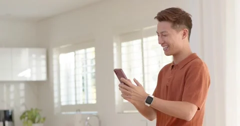 Diverse men in kitchen, beanie holding framed screen, orange polo raising purple Stock Footage 335836308