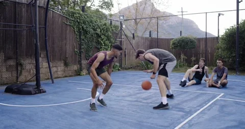 Diverse men playing one-on-one blue court gray tank bouncing ball causing purple Stock Footage 339983464